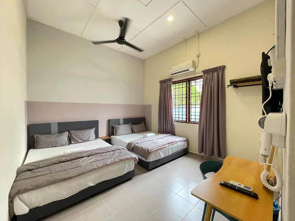 a bedroom with two beds and a table and a desk at Muslim Homestay Teluk Intan ( Hotel Style Room ) by Mr Homestay in Teluk Intan