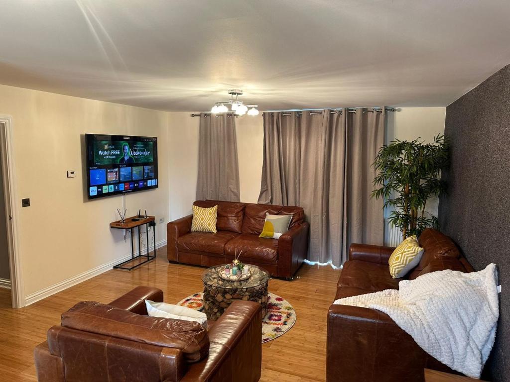 a living room with leather furniture and a flat screen tv at Long term cozy flat in Hendon