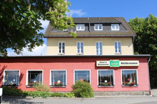 un edificio rojo y blanco con flores en las ventanas en Hotel Heilbrunnen, en Jöhstadt