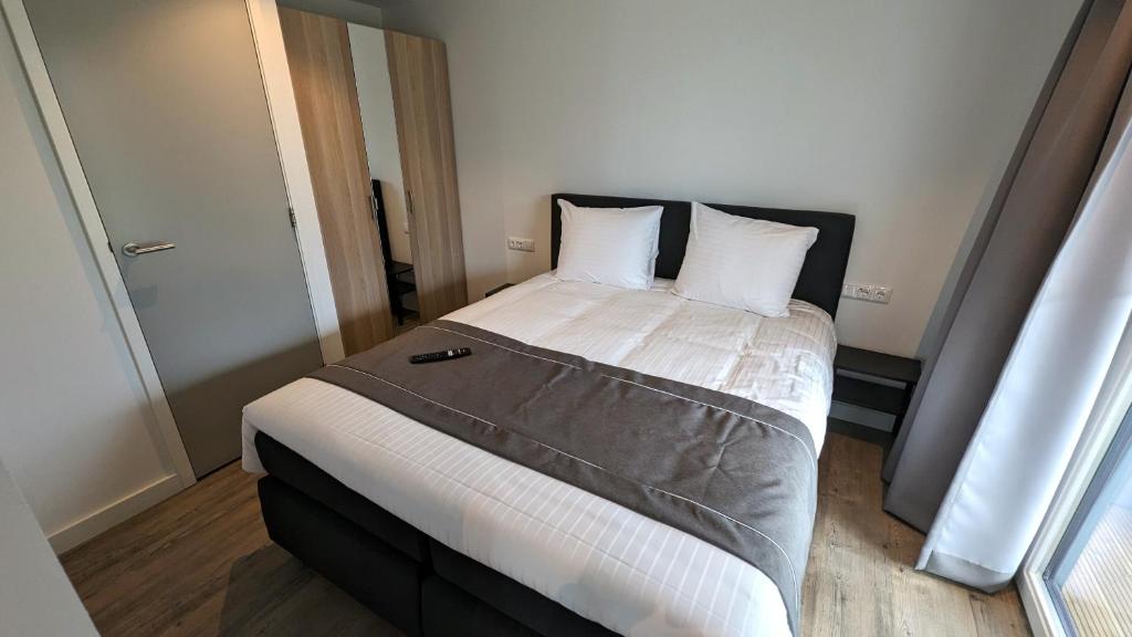 una camera da letto con un grande letto con lenzuola e cuscini bianchi di Antonius Hoeve Chalets a Oudenbosch