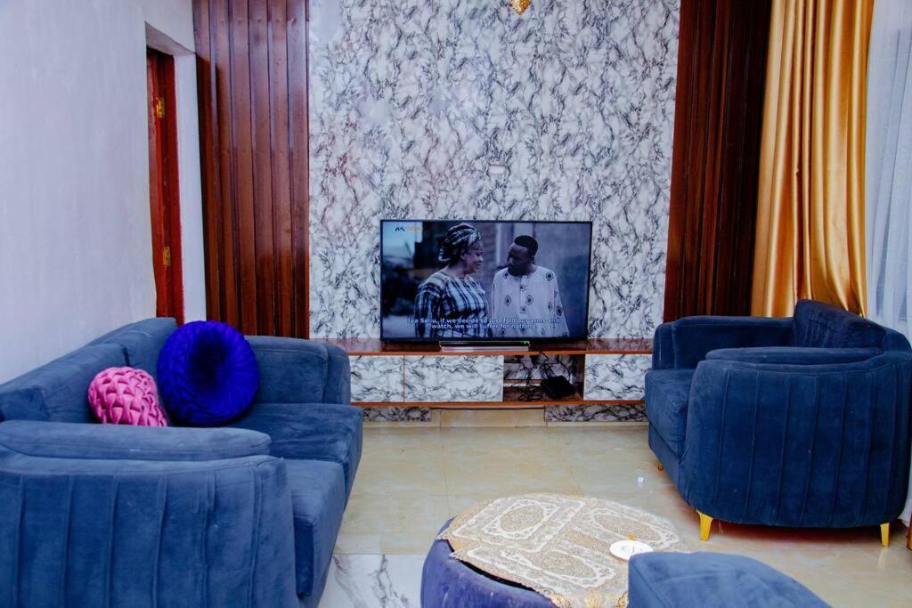 uma sala de estar com dois sofás azuis e uma televisão em Bellevue Apartment em Lagos
