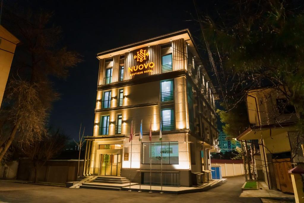 un bâtiment avec un panneau la nuit dans l'établissement Nuovo Boutique Hotel, à Tachkent