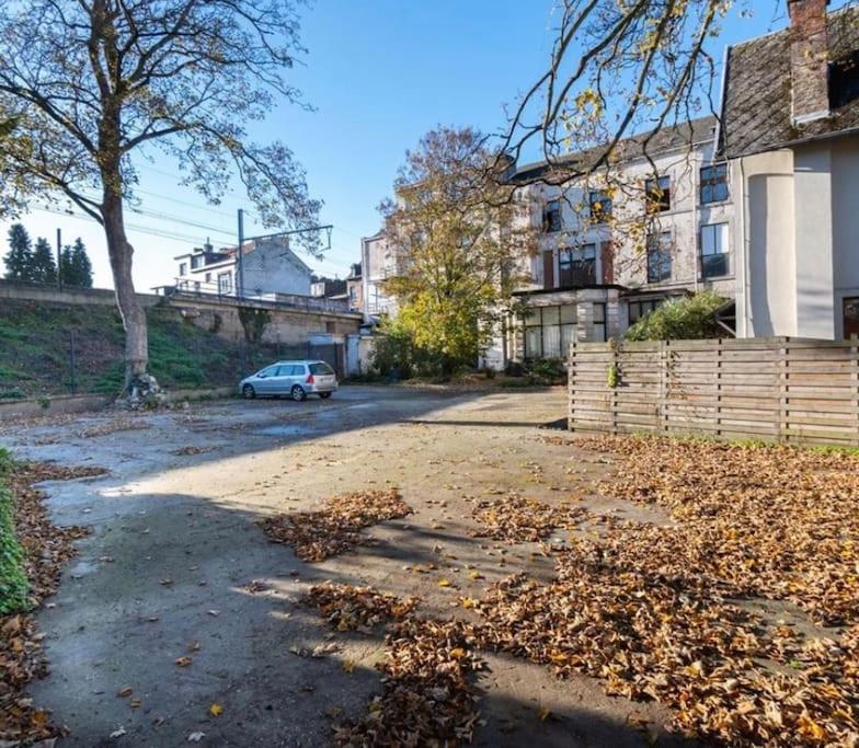 une voiture garée dans une rue avec des feuilles au sol dans l'établissement La Bonne-Femme, à Liège