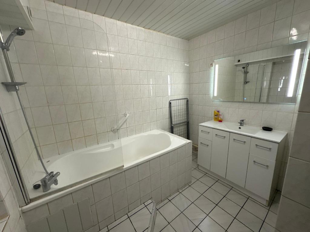 a white bathroom with a tub and a sink at Confortable appart 5 mins centre de valenciennes in Anzin
