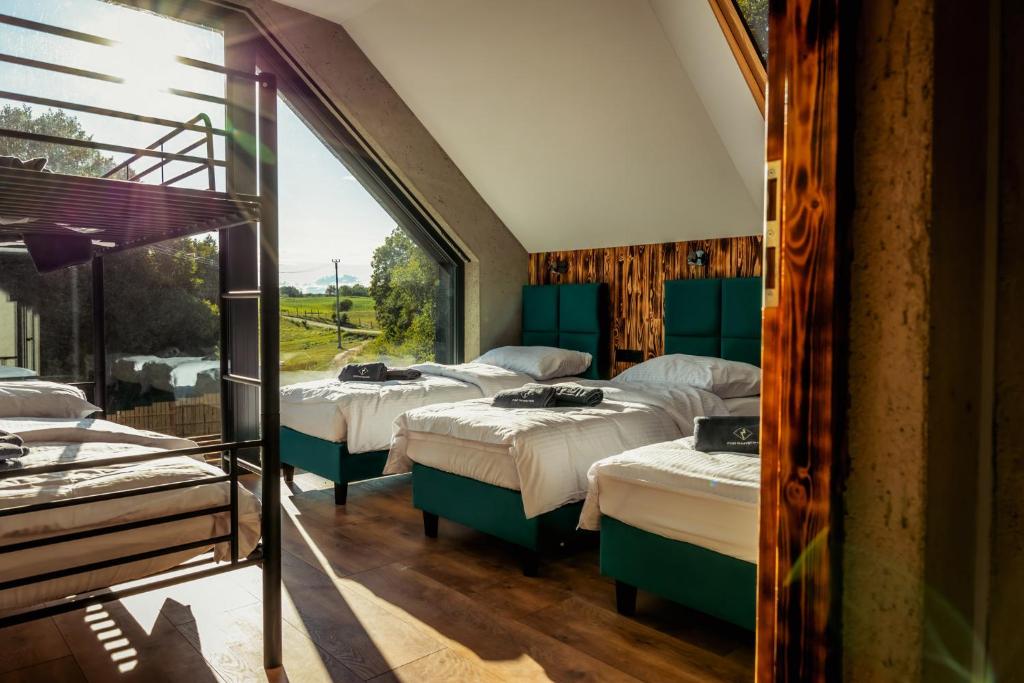 a room with four beds and a large window at Dom nad jeziorem Mazury - Pod Napięciem in Mrągowo