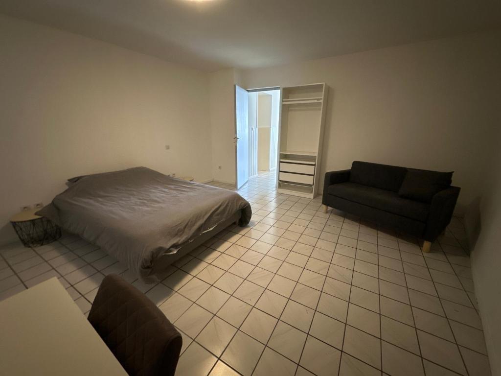 a bedroom with a bed and a couch and a table at Confortable appart 5 mins centre de valenciennes in Anzin