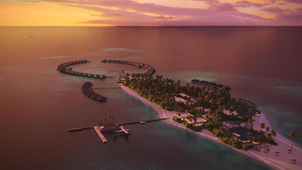 an island in the middle of the water at sunset at Veligandu Maldives Resort Island in Rasdhoo