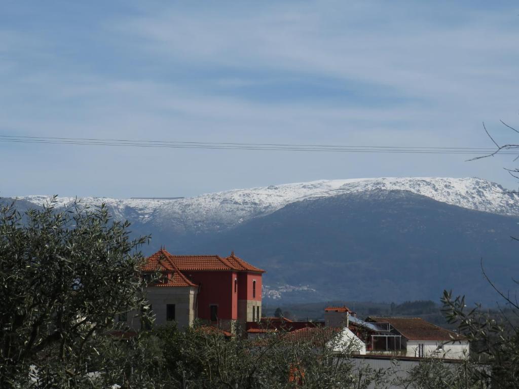 uma montanha coberta de neve à distância com casas em Solar dos Alperces - Serra da Estrela - Turismo de Aldeia em Travancinha