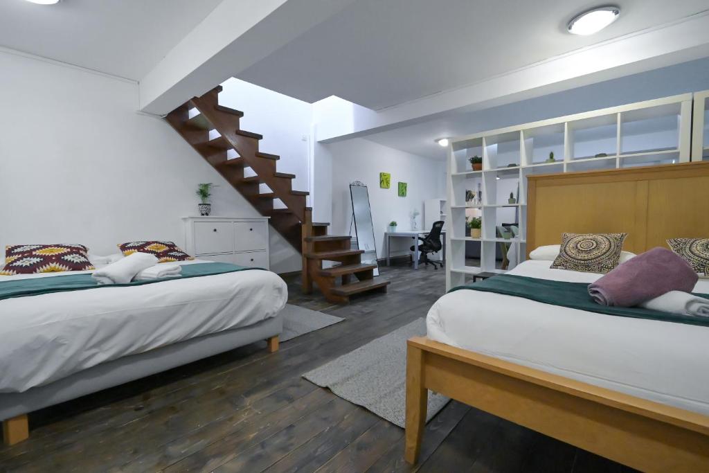 a bedroom with two beds and a staircase at Stoke Newington Studio by DC London Rooms in London