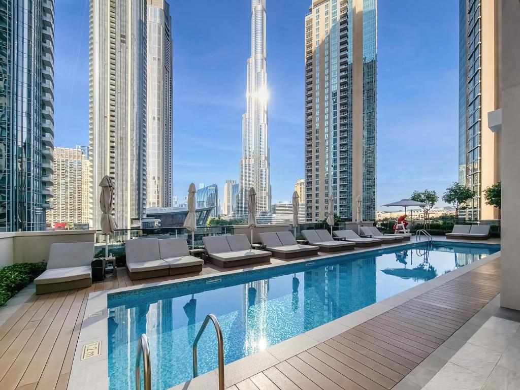 einen Pool mit Liegestühlen und einer Skyline der Stadt in der Unterkunft Act One Act Two by Emaar, Downtown Dubai in Dubai