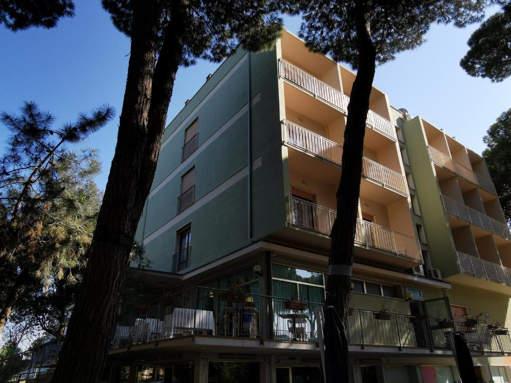 un edificio de apartamentos con árboles delante de él en Hotel Pine Beach, en Rosolina Mare