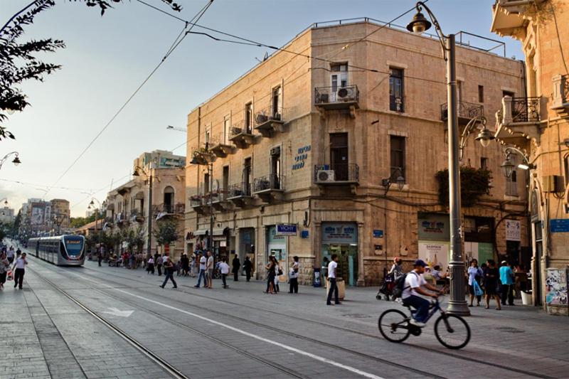 uma rua movimentada da cidade com pessoas a andar e um autocarro em Kaplan Hotel em Jerusalém