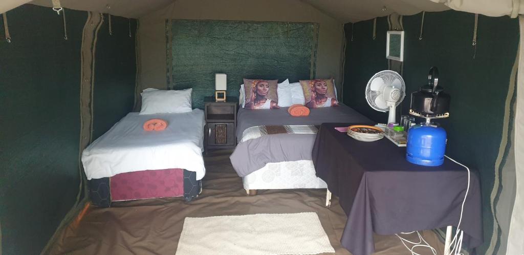 a bedroom with two beds and a table with a mirror at Paradise Nature Tented Camp in Groutfontein