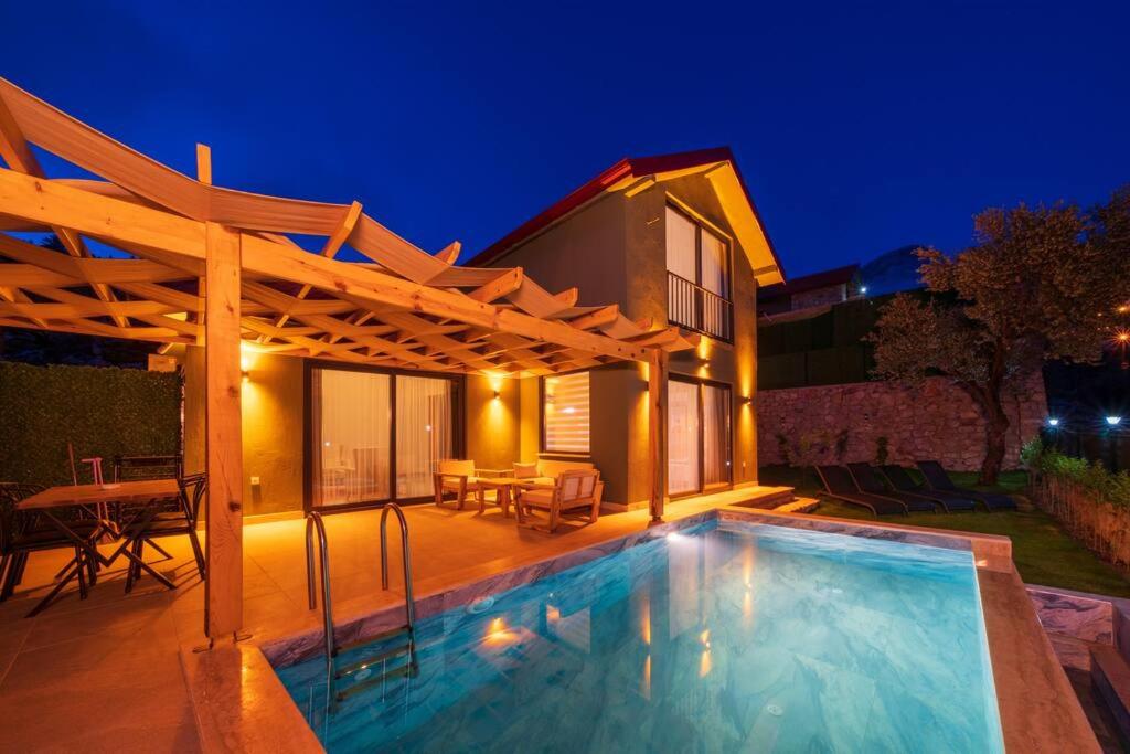 a swimming pool in front of a house at night at Villa Örencik in Fethiye