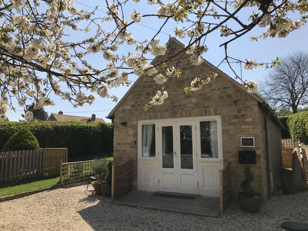 a small house with a white door in a yard at Cherry Tree Cottage in idyllic Cotswold village in Chipping Norton