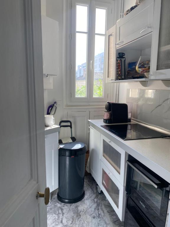 a white kitchen with a trash can and a window at Modern T2 app terrasse in Puteaux