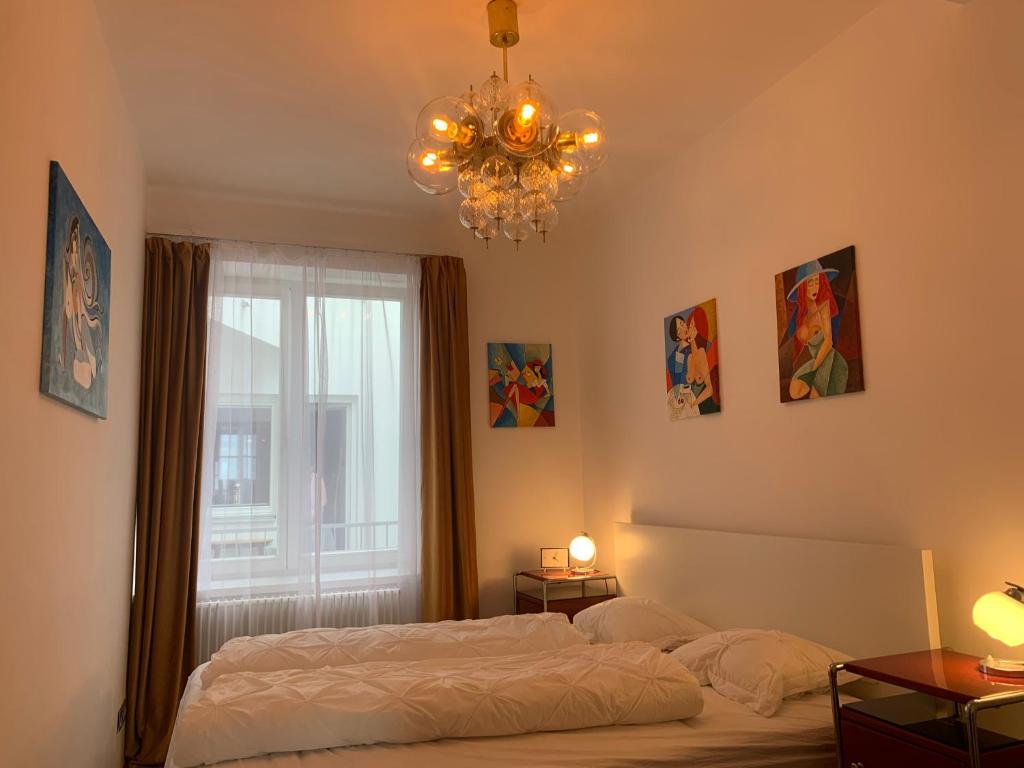 a bedroom with a bed and a chandelier and a window at Apartment Grossman in Hradec Králové