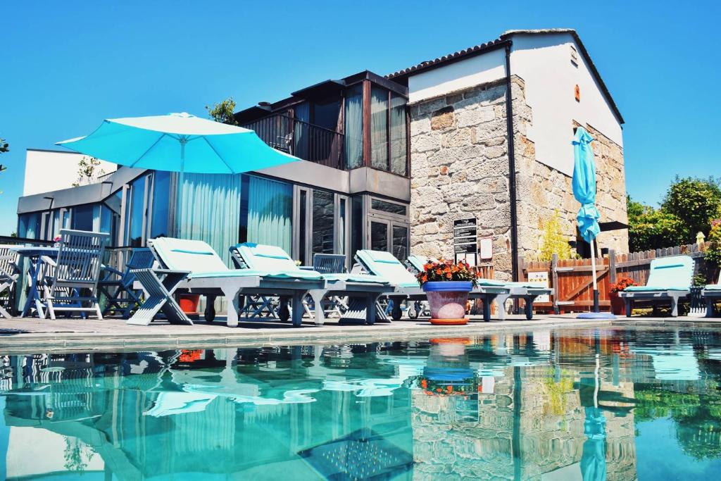 einen Pool mit einem Tisch, Stühlen und einem Sonnenschirm in der Unterkunft Quinta de San Amaro Rias Baixas in Meaño