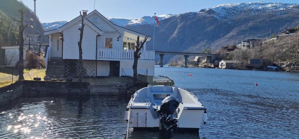 un barco estacionado en el agua junto a una casa en Sjötun Fjord Cabin, with boat, 