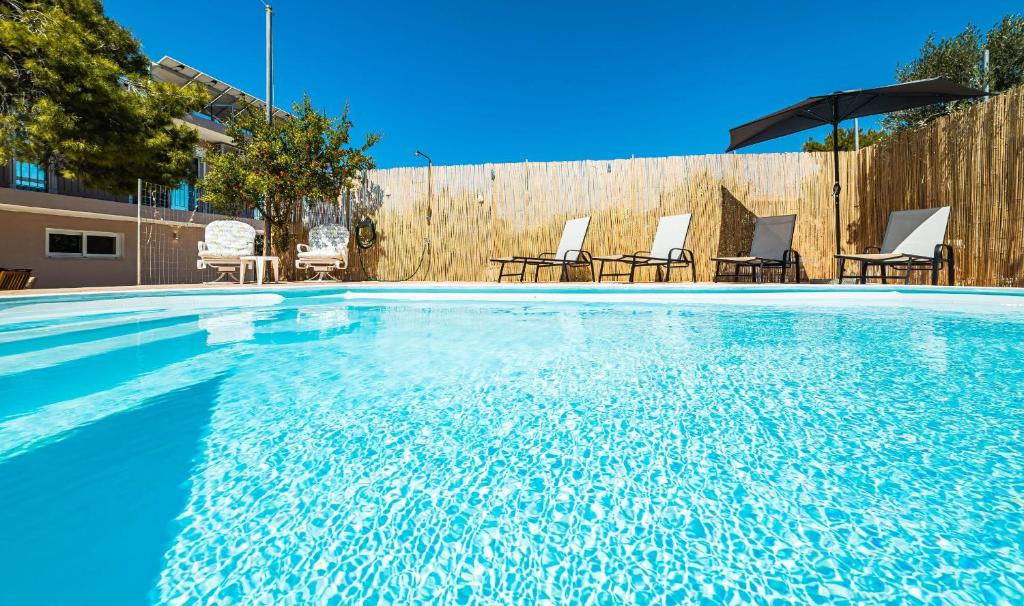 una piscina con sillas y sombrilla en J&K HOUSE SUITES, en Aghia Marina