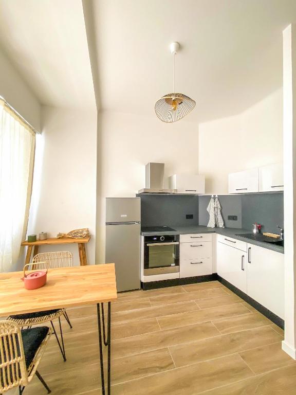 une cuisine avec des armoires blanches et une table à l'intérieur dans l'établissement Alsace Lorraine - Wifi, 3 pers, hyper centre, à Nice
