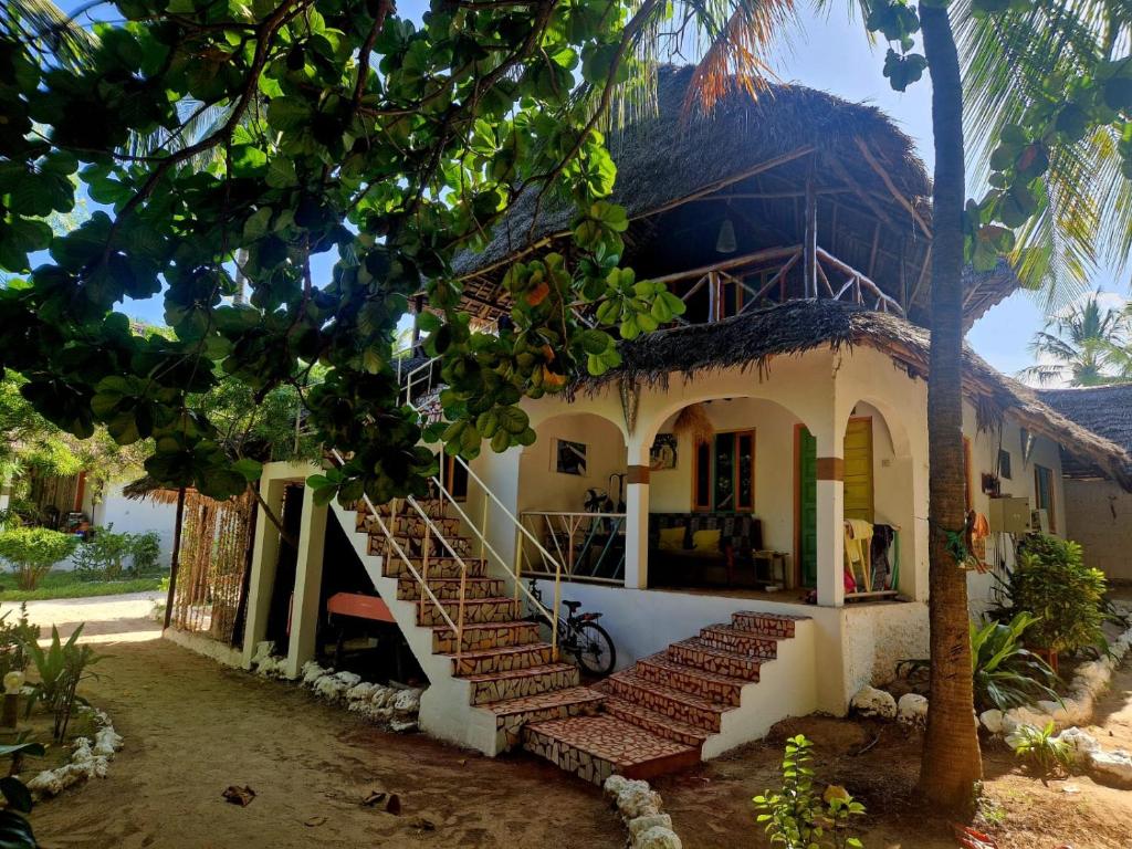 a white house with stairs in front of it at Fontaine Garden Village in Bwejuu