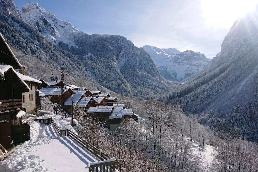 Blick auf ein schneebedecktes Bergtal mit Gebäuden in der Unterkunft Mountain house with two barns and a garden in Planay