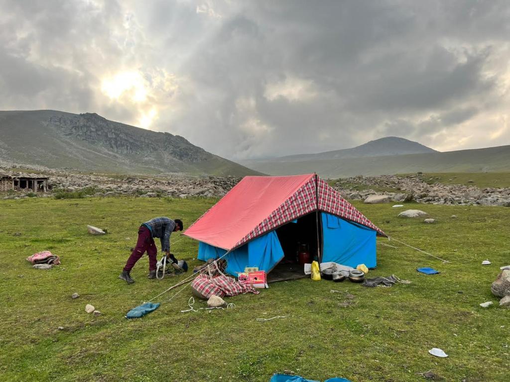 dwoje ludzi stojących obok namiotu na polu w obiekcie Kahn trekking guesthouse w mieście Nikri Dhokri