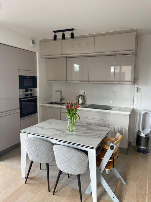 une cuisine avec une table, des chaises et un vase de fleurs dans l'établissement Cosy Appartement, à Saint-Germain-en-Laye