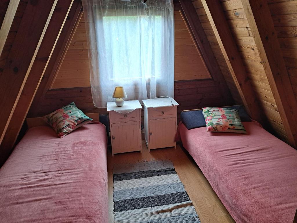 2 camas en un ático con ventana en Domek Ostrowo en Ostrowo