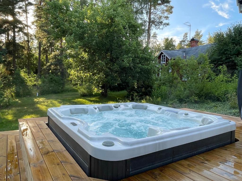 a hot tub sitting on top of a wooden deck at Genuine 100 year old countryside cottage in Rimbo