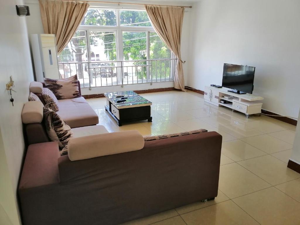 a living room with a couch and a tv at Deluxe Rooms in Shared Apartments in Dar es Salaam