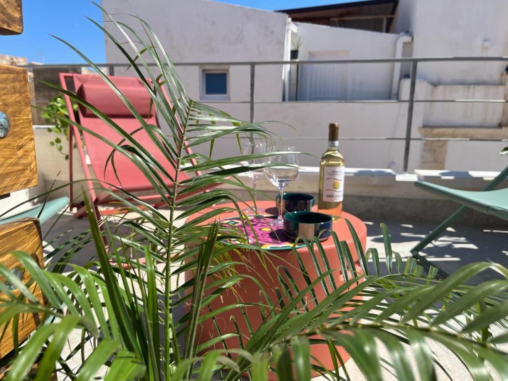 a plant in front of a table with a bottle of wine at Aglaia apartment residence delle tre grazie in Syracuse