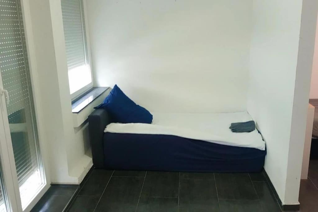 a small bed in a room with two windows at Celine Zimmer in Heilbronn Zentrum in Heilbronn