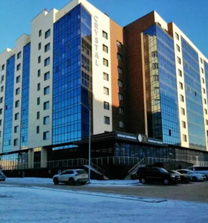 um grande edifício com carros estacionados num parque de estacionamento em ЖК Crystal em Karaganda