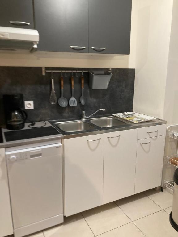 a kitchen with white cabinets and a sink at T2 centre ville RERB pour 2-4 personnes in Palaiseau