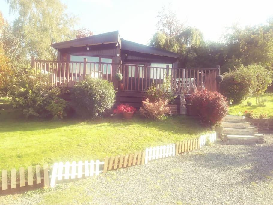een klein huis met een hek ervoor bij Anne's Lodge Caerberis Holiday Park, dog friendly in Builth Wells