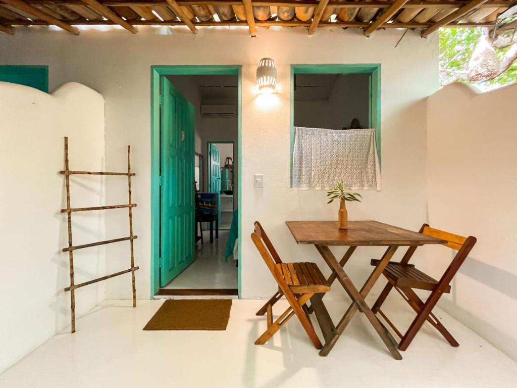 uma sala de jantar com mesa e cadeiras e uma porta verde em Encanto Caraíva em Caraíva