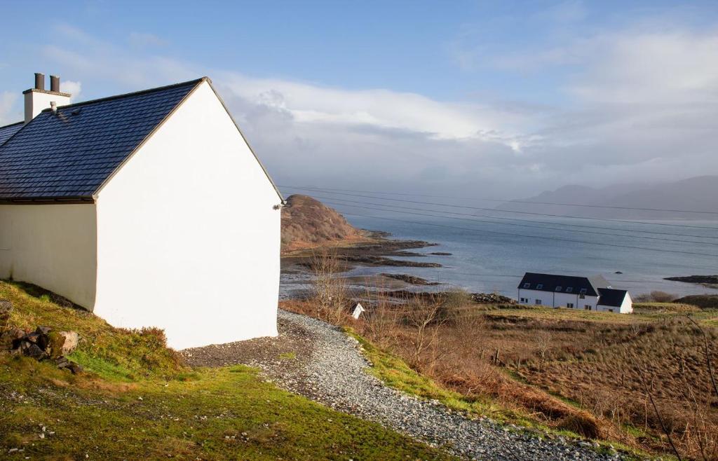 un edificio blanco en una colina junto al océano en Skye Nadair, en Isleornsay