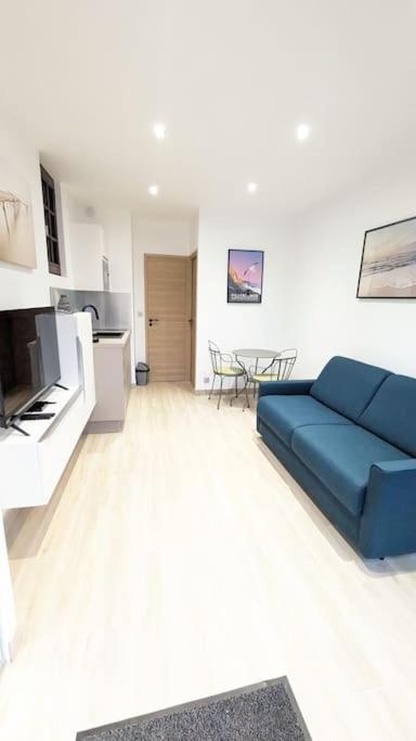 un salon avec un canapé bleu et une cuisine dans l'établissement Le Méridien, studio rénové avec terrasse, 8 min à pieds du centre ville, à Villers-sur-Mer