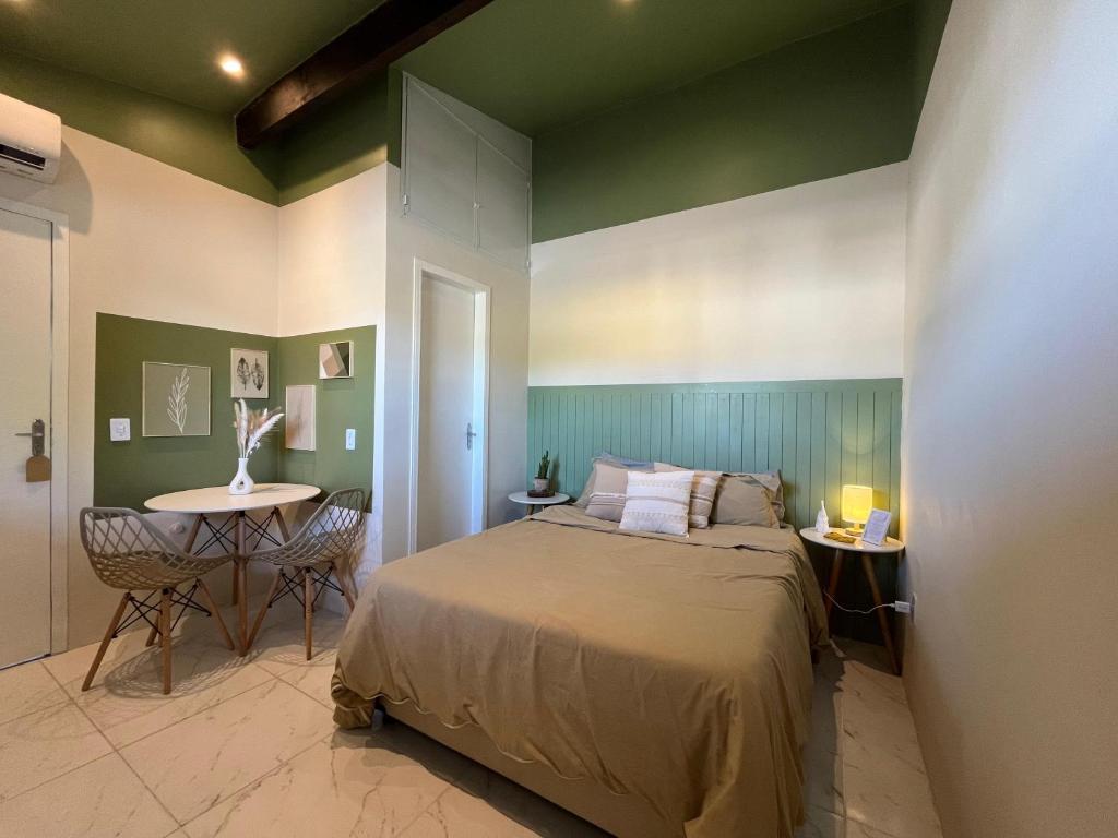 Aconchegante Suite green في نيتيروي: غرفة نوم بسرير وطاولة مع كراسي