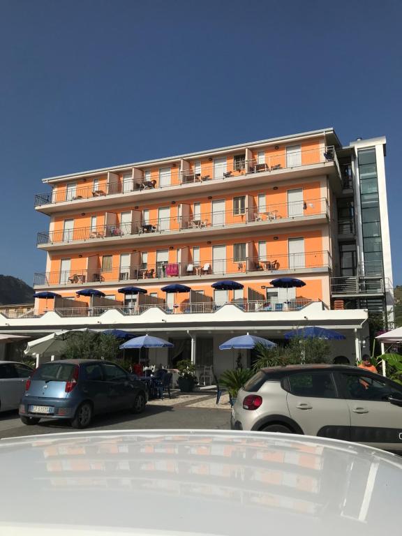 un grand bâtiment avec des voitures garées dans un parking dans l'établissement Hotel Ristorante Santa Maria, à Amantea