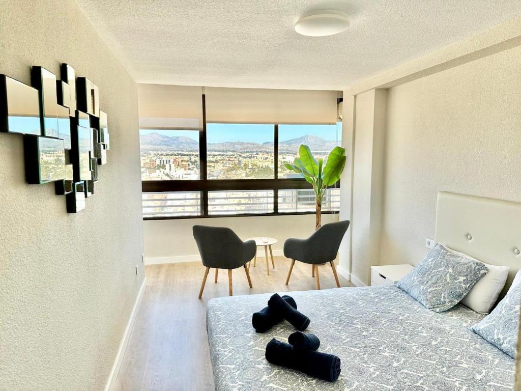 a bedroom with a bed with two chairs and a window at Luceros Sky in Alicante