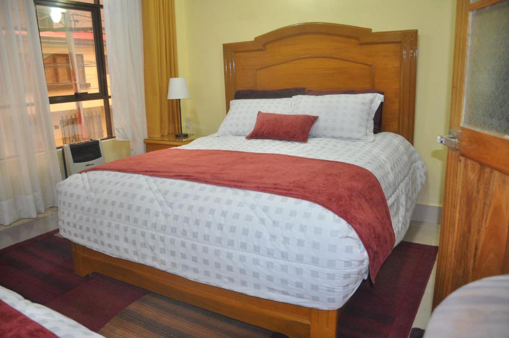 ein Schlafzimmer mit einem großen Bett mit einem roten Kissen darauf in der Unterkunft COMODORO DEPARTAMENTOS in Oruro
