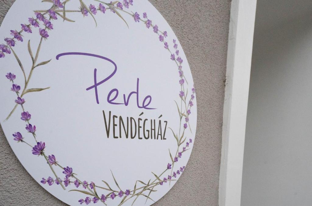 un plato con una corona de flores púrpura en una pared en Perle Vendégház, en Kesztölc