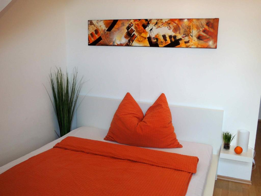 メードリングにあるAppartement Föhrenvillaのオレンジの枕と壁画が備わるベッドルーム1室