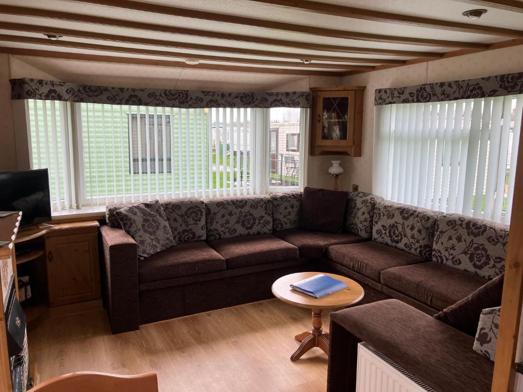 a living room with a couch and a table at Spacious caravan with DG, CH & veranda in Skegness