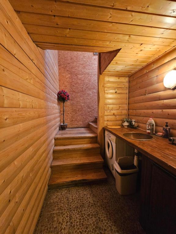 a bathroom with a sink and a wooden wall at Svečiu Namai in Pagiriai