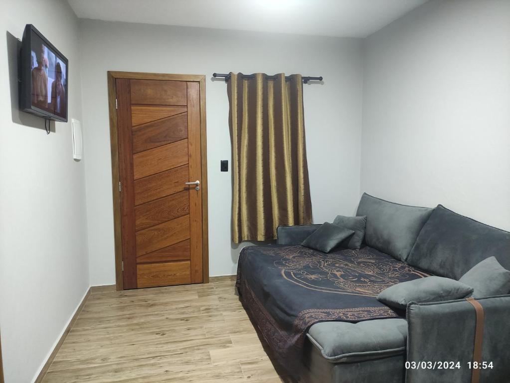 uma sala de estar com um sofá e uma porta de madeira em kitnets Porto Marujo em Paranaguá