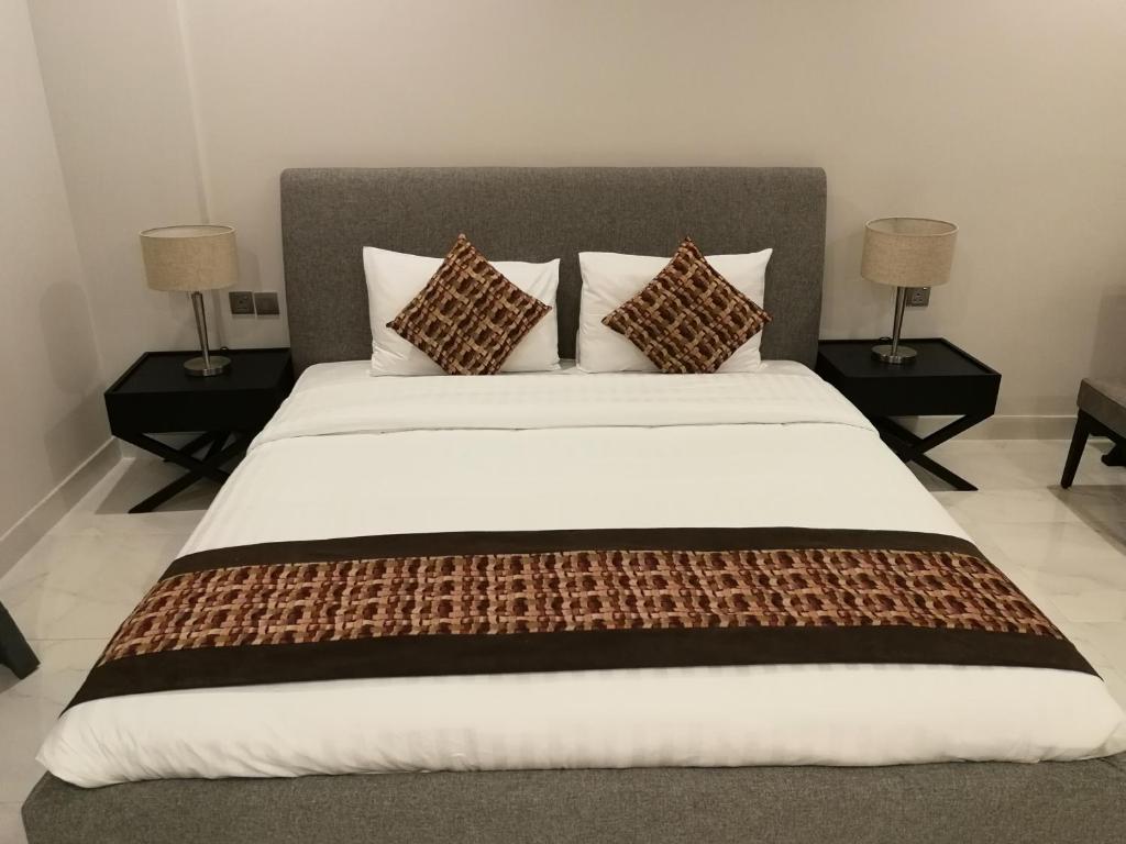 a bedroom with a large bed with three pillows at Infinity Juffair Suites in Juffair